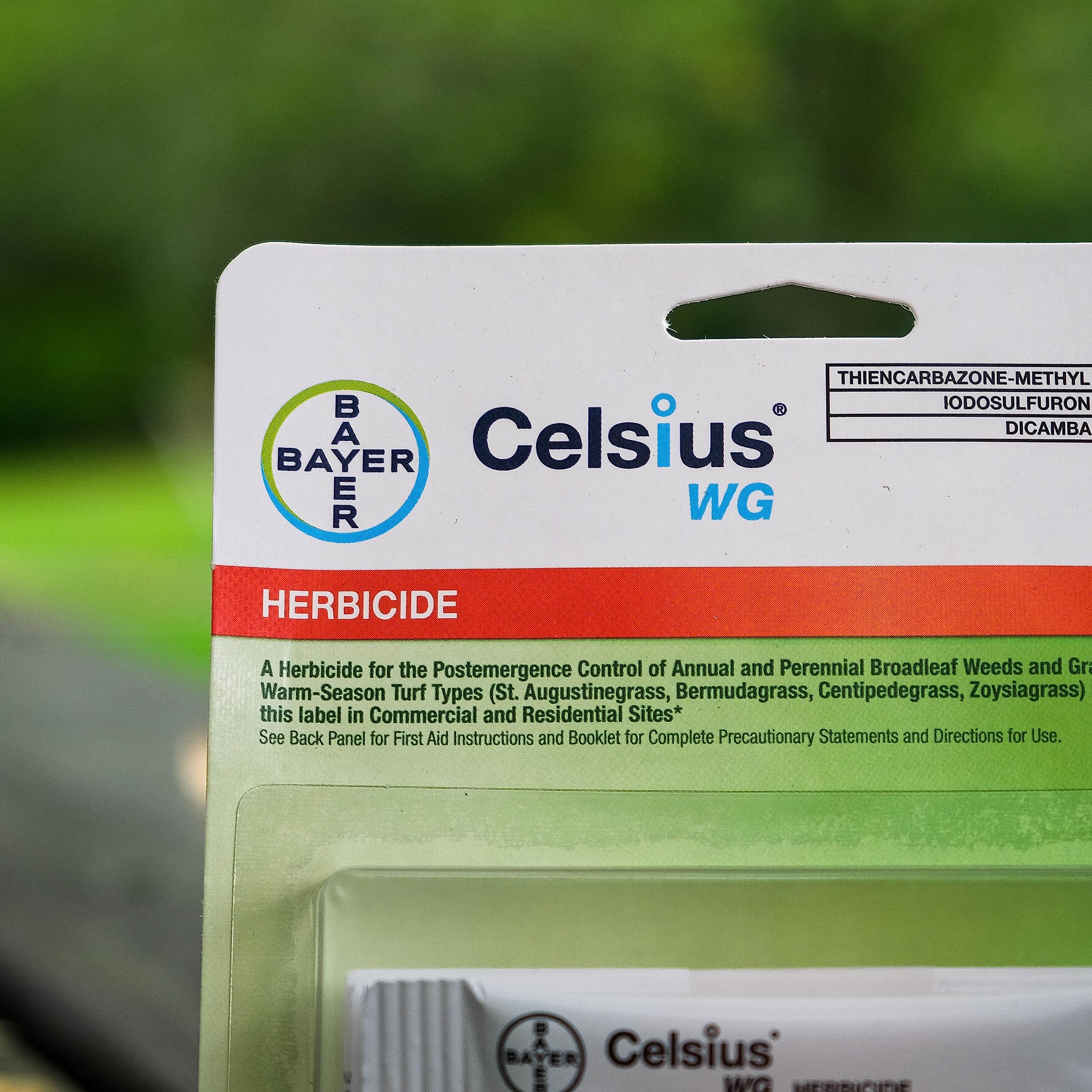 Bayer Celsius WG paquete junto a regadera para comparar tamaño y conveniencia