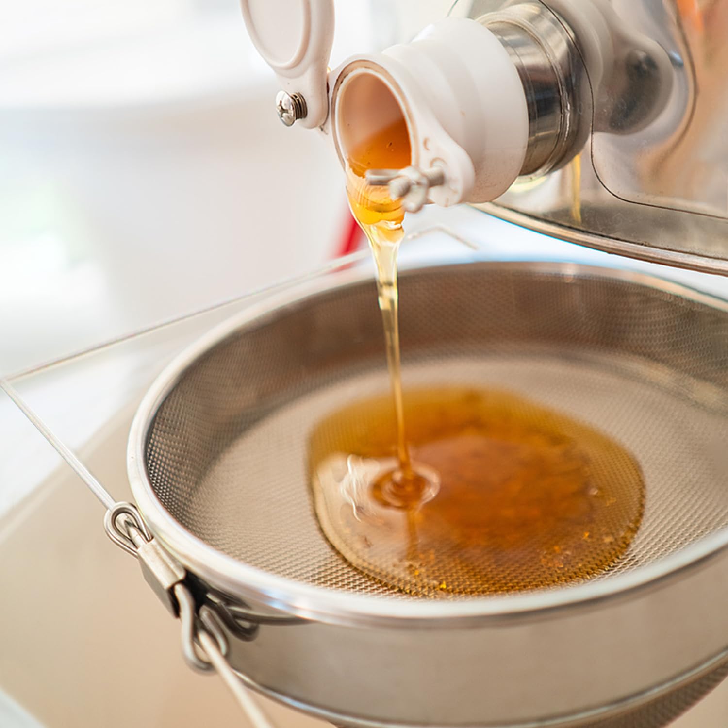 BEEKNOWS colador en cocina con tarros de miel ilustrando uso doméstico profesional