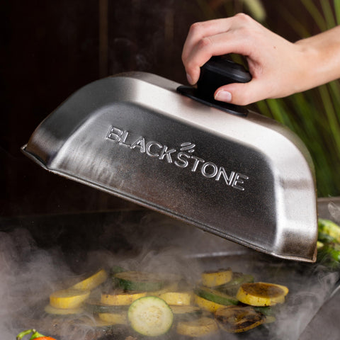 Blackstone cubierta en uso sobre plancha con hamburguesas, acelera derretido y cocción