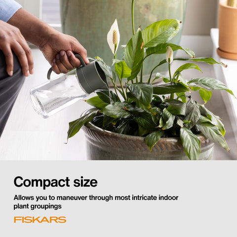 Fiskars regadera junto a una taza para comparar tamaño compacto