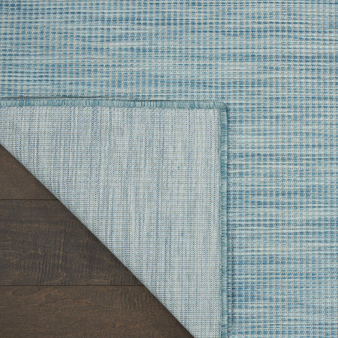 Nourison Positano Aqua comparación de tamaño junto a escalera para escala visual