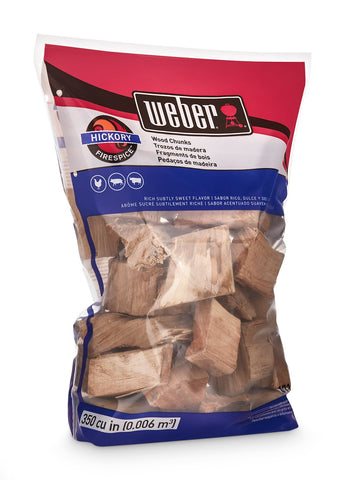 Weber trozos de Hickory sobre parrilla generando humo para sabor